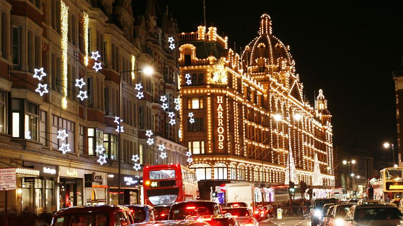 Spot Harrods dressed up for the festive season with its iconic Christmas lights. Credit: London & Partners. Image courtesy of London & Partners. Photo of a road with Harrods store decorated in Christmas lights.