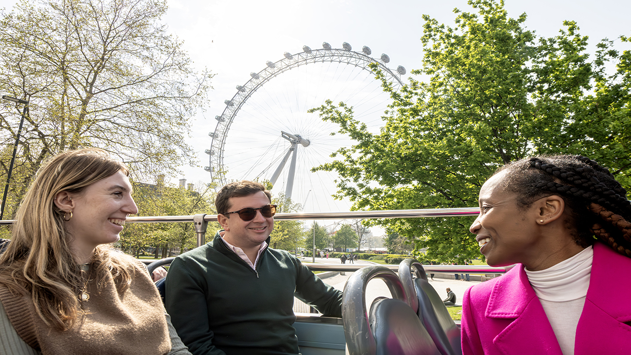 Enjoy a day out exploring London and its many sights on the London Hop-On Hop-Off bus tour. ©London & Partners/Michael Barrow A group of three friends are enjoying a sunny day on the top deck of the Hop-On Hop-Off tourist bus passing by the London Eye.
