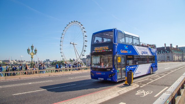 Blue double-decker bus driving past South Bank and the London Eye on a London bus tour.