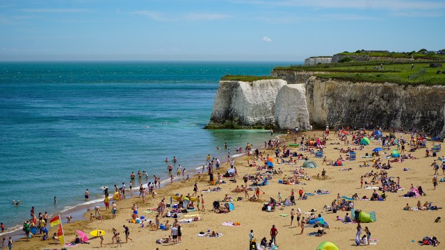 Aerial view of the beach at Botany Bay near Broadstairs on a summer's day, with crowds of beachgoers set up on the beach and some taking a dip in the sea.