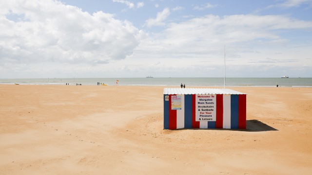 Sandy beach with colourful beach hut on a sunny day in Margate, Kent.