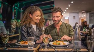 Two people eat dinner on a river thames cruise.