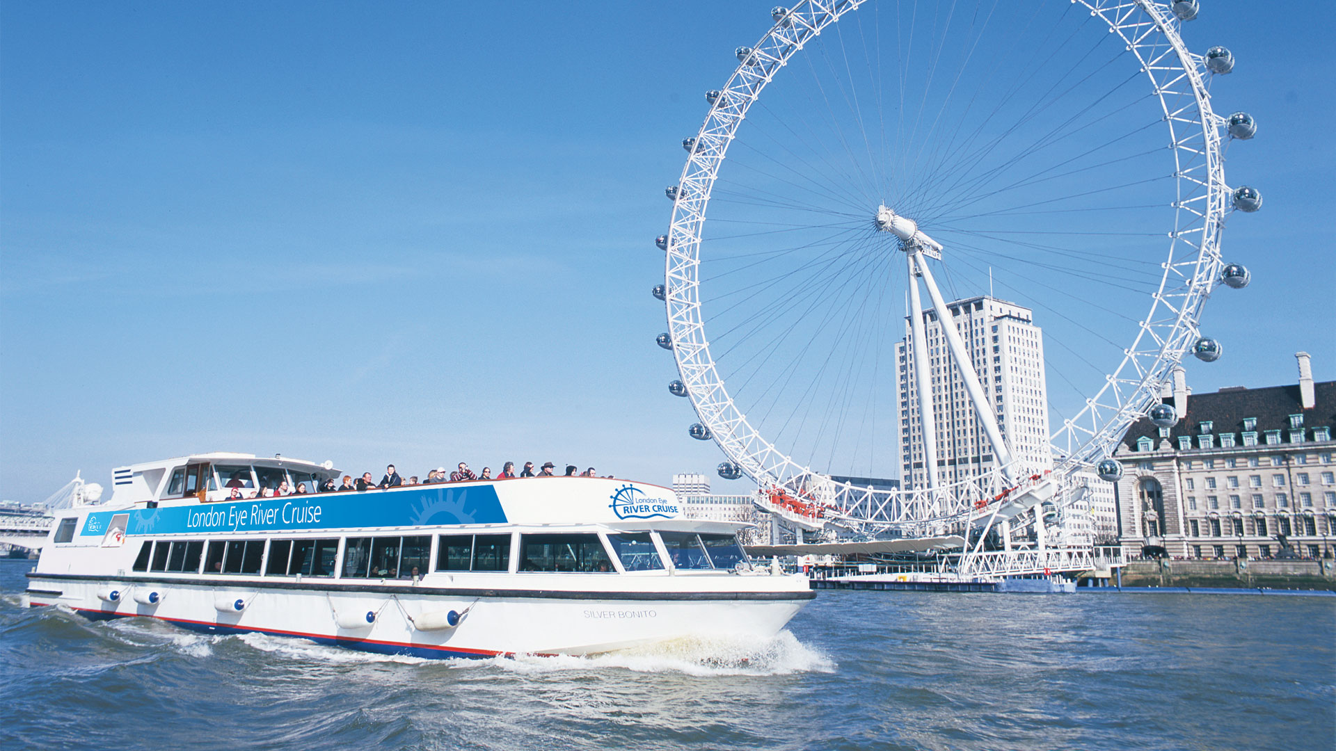 Admire spectacular views of the London Eye along with London’s top landmarks. Image courtesy of Golden Tours. River cruise on the Thames in front of the London Eye.