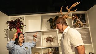 A man and a woman are trying out head props on display in the exhibition space at Shakespeare's Globe Theatre.