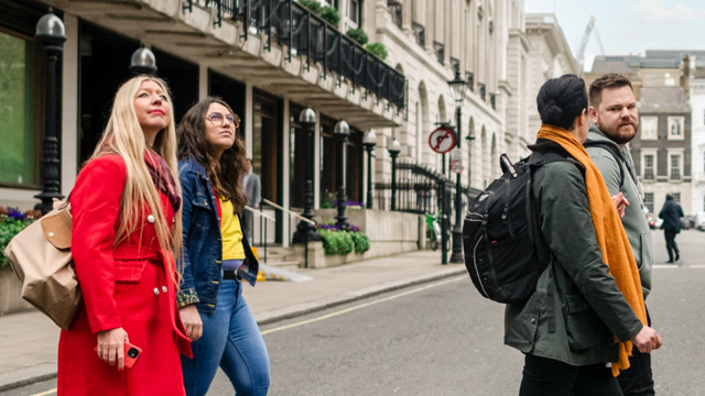 A group of two women and two men crossing the streets of St James's in London, and looking at the sights.