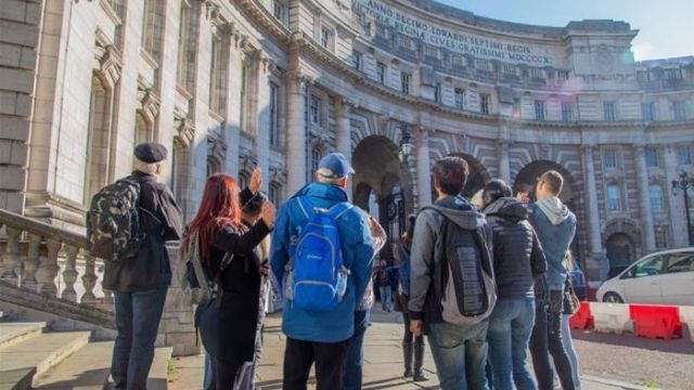 A group of tourists marvel at a historic building in London on the Royal Walking Tour, Changing of the Guard. 