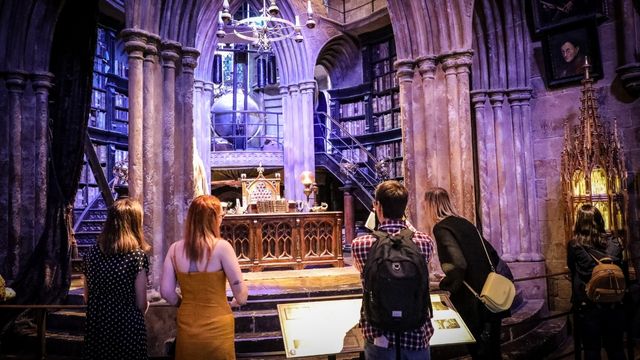 A group of tourists look into a replica of dumbledoors office at warner bros studios.