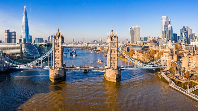 An aerial view of Tower Bridge and the river Thames, with The Shard on the left and the City of London on the right.