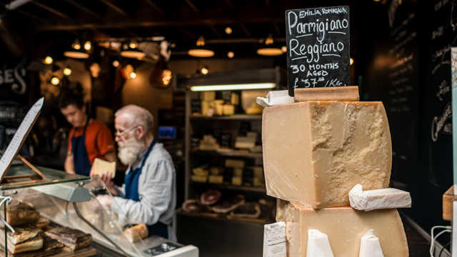 Chalk board on top of stacks of parmesan with a cheesemonger at a Borough Market stall