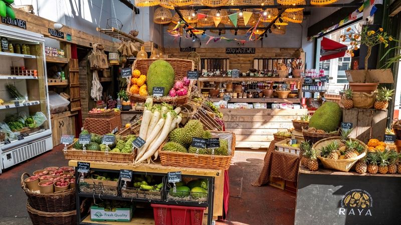 A stall at Borough Market selling a variety of produce including shelves of fruit and vegetables, fridges with fresh ingredients