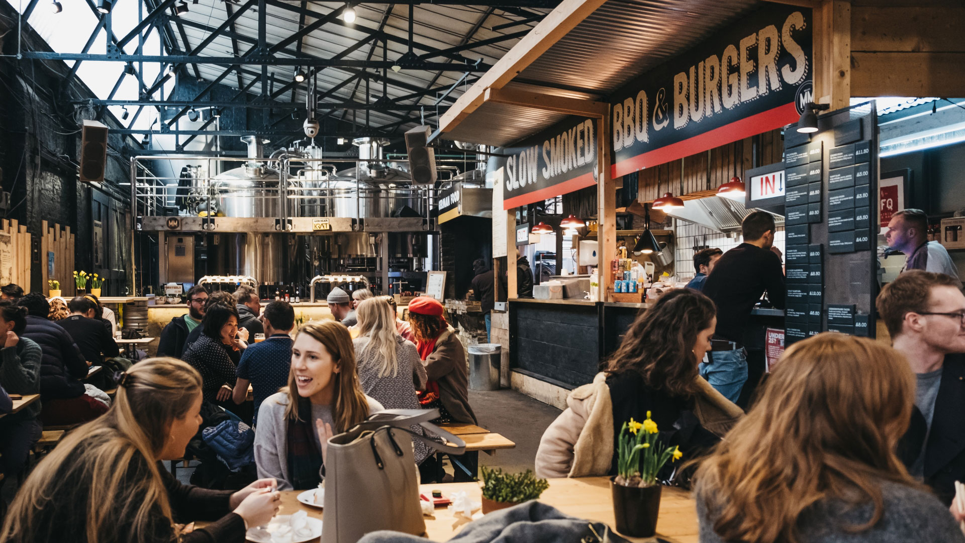 Choose from one of the many ethical vendors at Mercato Metropolitano. Credit: Shutterstock. Image courtesy of Shutterstock. Benches with groups of people sat chatting and enjoying food at an indoor market with different food stalls cooking fresh food