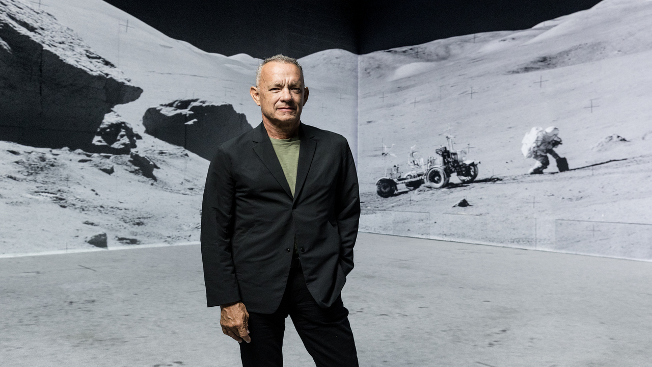The Moonwalkers: A Journey with Tom Hanks. Photo credit: Justin Sutcliffe. Image courtesy of Lightroom. Tom Hanks in font of immersive exhibition of moon landing.