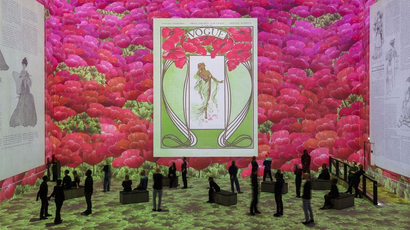 Experience the Vogue: Inventing the Runway exhibition, with graphics from Conde Nast ©Justin Sutcliffe. Image courtesy of Lightroom. Vogue newspaper graphic surrounded by flowers on walls at Lightroom.