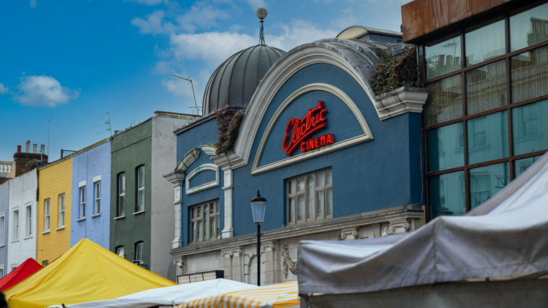 Stop by Electric Cinema on buzzy Portobello Road where you can feel right at home with bed, sofa and armchair seating options. Credit: Shutterstock. Image courtesy of Shutterstock. A photo of the light blue front exterior of Electric Cinema in Portobello with its trademark red neon logo and Portobello Road market stalls in the foreground