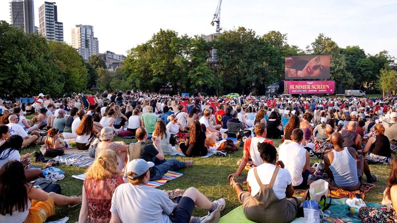 Book your free ticket to Vauxhall Summer Screen film showings on weekdays throughout summer. Credit: Neil Massey. Image courtesy of Vauxhall Summer Screen. A photo of a crowd of people sat in Vauxhall Pleasure Gardens on picnic rugs and blankets with snacks and drinks and a giant screen in front of them showing a film during the Vauxhall Summer Screen