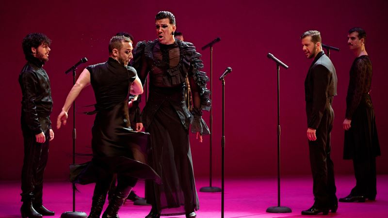 Get ready to move to the music during London's annual Flamenco Festival. Credit: Marcos G. Punto. Image courtesy of Sadler's Wells. A photo of five men dressed in black on stage with microphones dancing and singing with a pink background