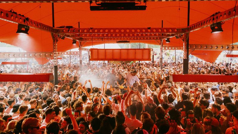 Get on your dancing gear and head to Peckam Rye in south London for Gala Festival. Credit: Jake Davis. Image courtesy of Khroma Collective. A photo of a stage at Gala festival with crowds of people stood underneath a large red rent around a stage of DJs, overhead lighting and a smoke machine