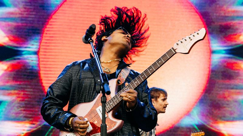 Be serenaded by some of the genre's best acts at Jazz Cafe Festival. Credit: Sophie Harbinson. Image courtesy of Jazz Cafe. A close up photo of a musician playing a guitar whilst throwing his head back with a microphone in front of him and psychedelic visuals on the screen behind