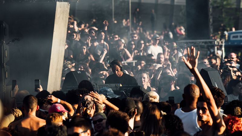 Find some of the biggest names in electronic music at Maiden Voyage in south London. Credit: Maiden Voyage. Image courtesy of Maiden Voyage. A photo of DJ, Jeff Mills, with headphones on and DJ equipment surrounded by hundreds of people dressed in festival outfits at Maiden Voyage festival