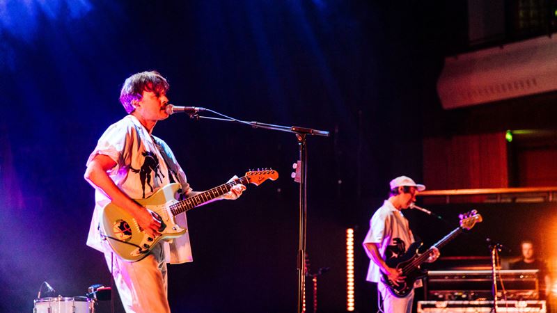 Find an artist-curated selection of talent at Southbank Centre's annual Meltdown festival. Credit: Victor Frankowski. Image courtesy of Southbank Centre. A photo of two men performing onstage each with a guitar whilst singing into a microphone and colourful lights behind them