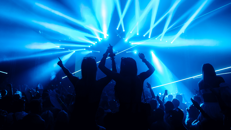 Party all day into the night at We Are Fstvl in Dagenham. Credit: Laurence Howe Photo. Image courtesy of Lightfoot Agency. Silhouette of two friends on shoulders in the crowd in front of stage with glowing blue light lasers
