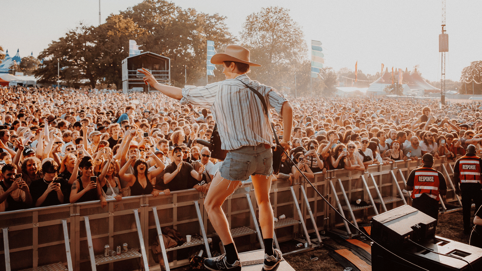Join the crowds that flock to Wide Awake festival to see the latest up-and-coming talent. Image credit: Luke Dyson. Frontman dressed in check shirt, denim shorts and hat sings to the crowd