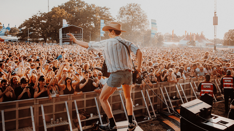 Join the crowds that flock to Wide Awake festival to see the latest up-and-coming talent. Credit: Luke Dyson. Image courtesy of Luke Dyson. Frontman dressed in check shirt, denim shorts and hat sings to the crowd