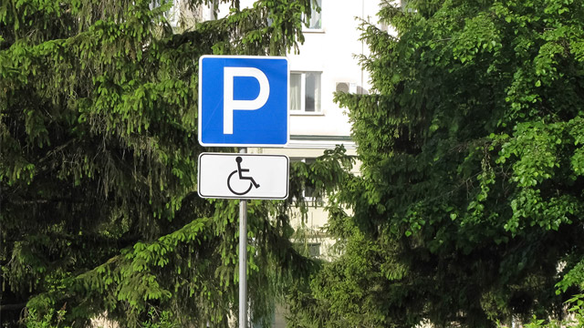 Blue parking sign with a wheelchair symbol in black and white below.