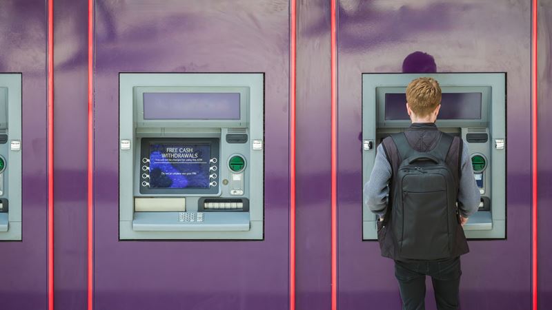 Withdraw money to use in London at cash machines across the city. Credit: Shutterstock. Image courtesy of Shutterstock. A photo of a wall of cash machines with one man on the end with his back to the camera using one of them