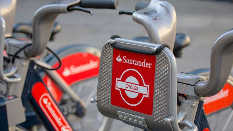 A close up photo of two Santander bicycles at a docking station with red logos on the front and sides