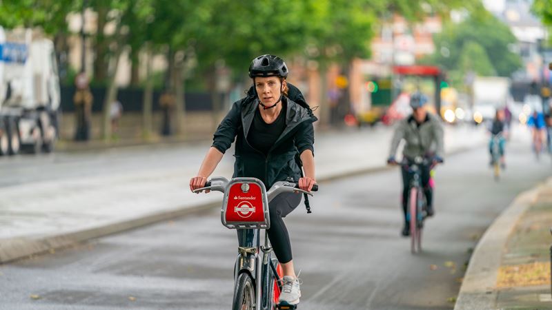 Cycle around London safely and easily using the city's dedicated cycle lanes. Credit: Shutterstock. Image courtesy of Shutterstock. A photo of a woman on a Santander bicycle wearing a helmet and riding in a London cycle lane with cyclists following close behind her