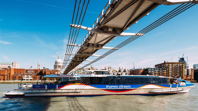 Hop aboard the Thames Clipper Cyclone for a scenic journey across the city. Credit: Thames Clippers. Image courtesy of Thames Clippers. An image taken from river level as Thames Clippers' Cyclone river boat passes under the Millennium Bridge, with St Paul's Cathedral in the background.