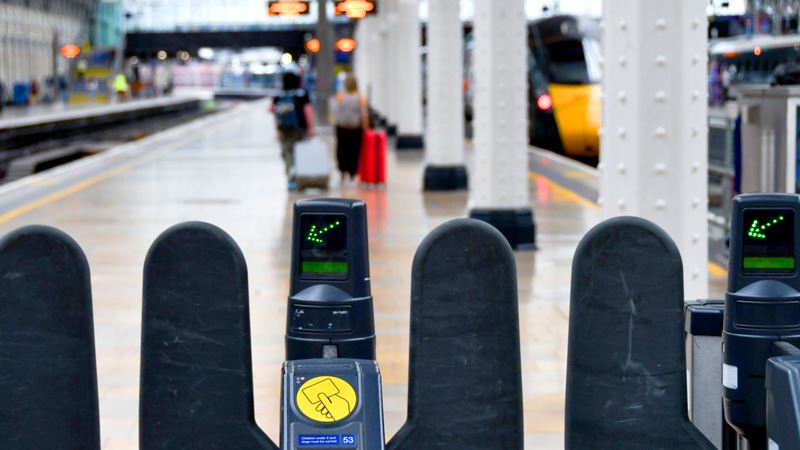 A photo of ticket barriers at a London train station with a contactless card reader and green arrow 