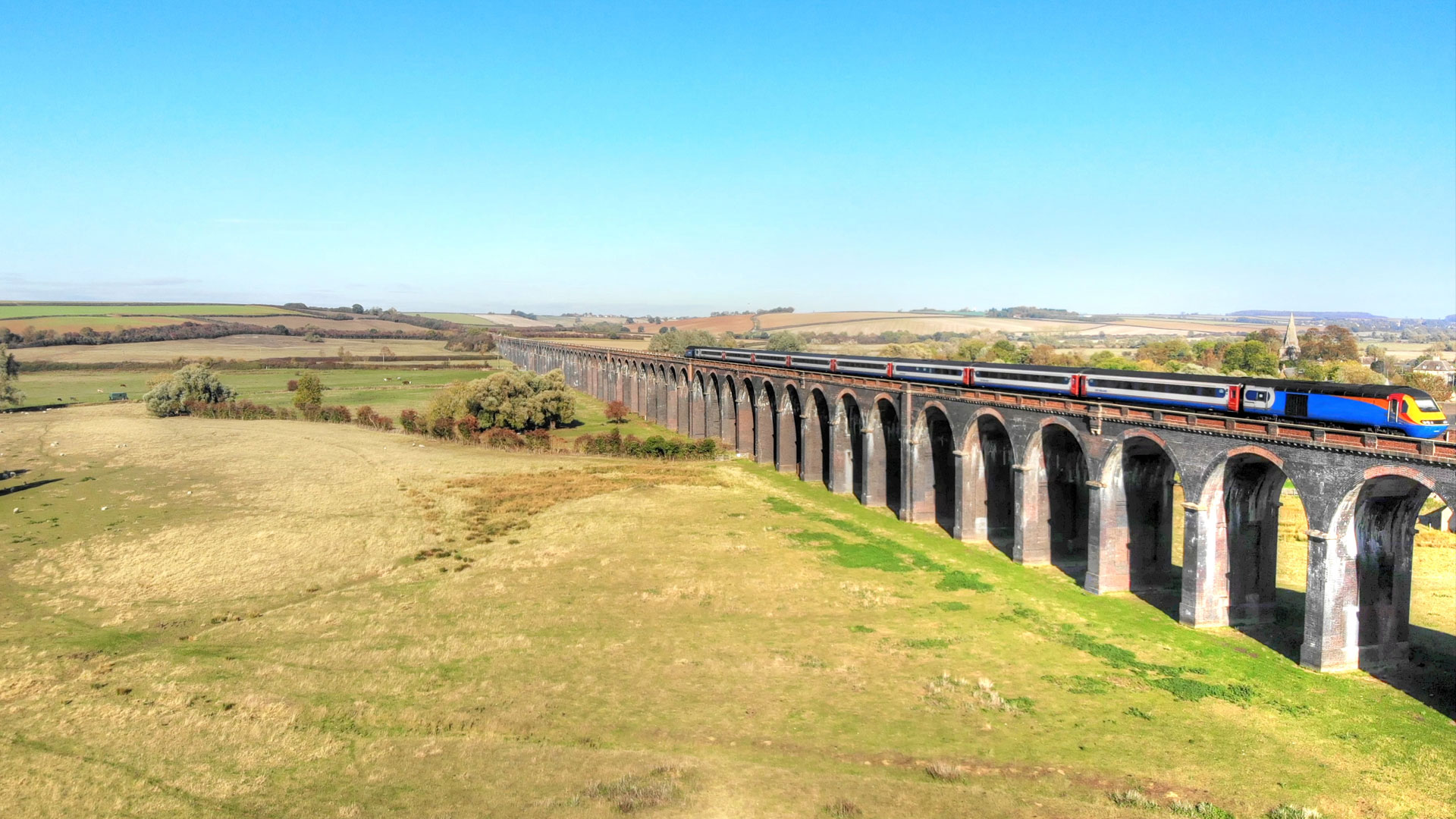 Train whizzing past the English countryside. Image courtesy of Shutterstock. Blue, white and red train whizzing past the green English countryside.