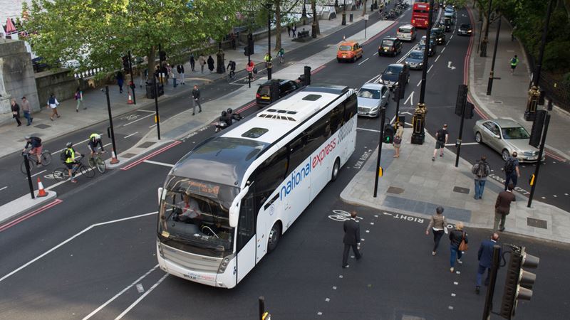 A photo of a National Express coach driving through a road in Westminster in London from above, with cars following nearby