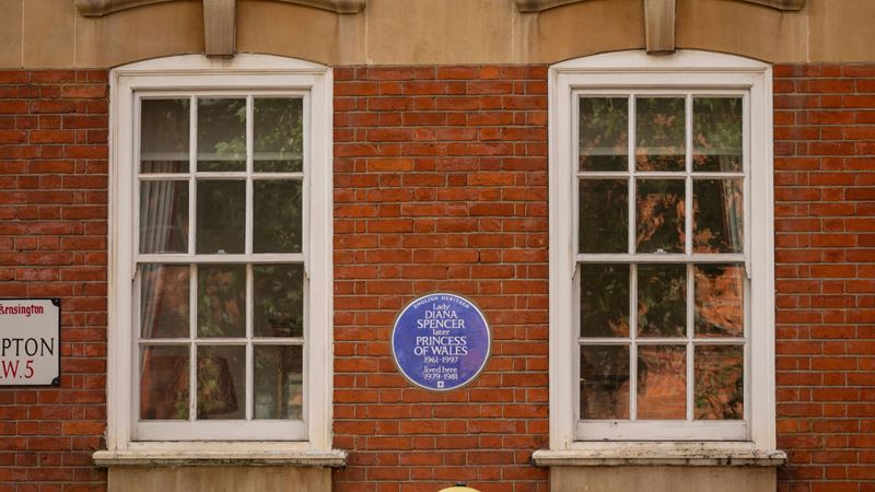 Princess Diana blue plaque on a red wall with windows in london.