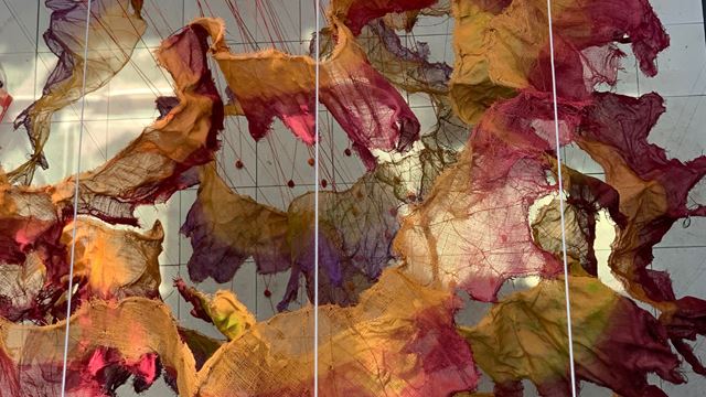Fabric installation representing leaves hanging from ceiling in building.