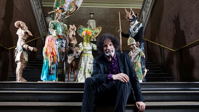 Kew Locke sitting on steps of exhibition at the British Museum. 