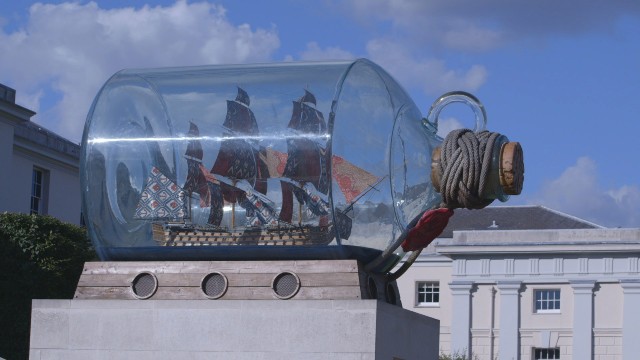 A ship in a bottle exhibit against the blue skies at the National Maritime Museum.