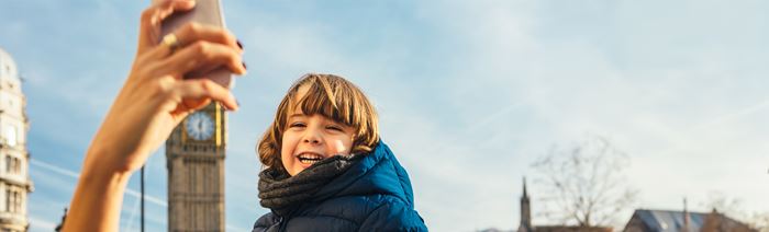 A boy smiling in front of Big Ben on a sunny winter day