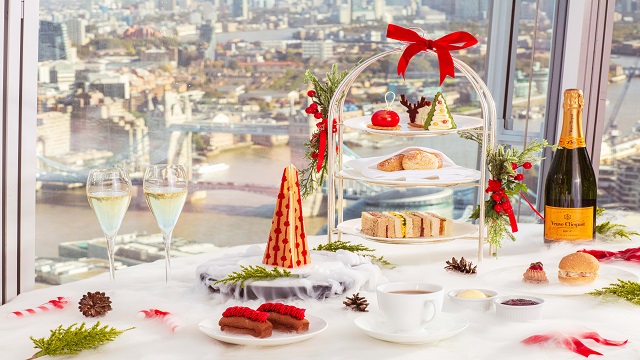 A table covered in sweet and savoury treats at a festive afternoon tea overlooking the London skyline from the shard.