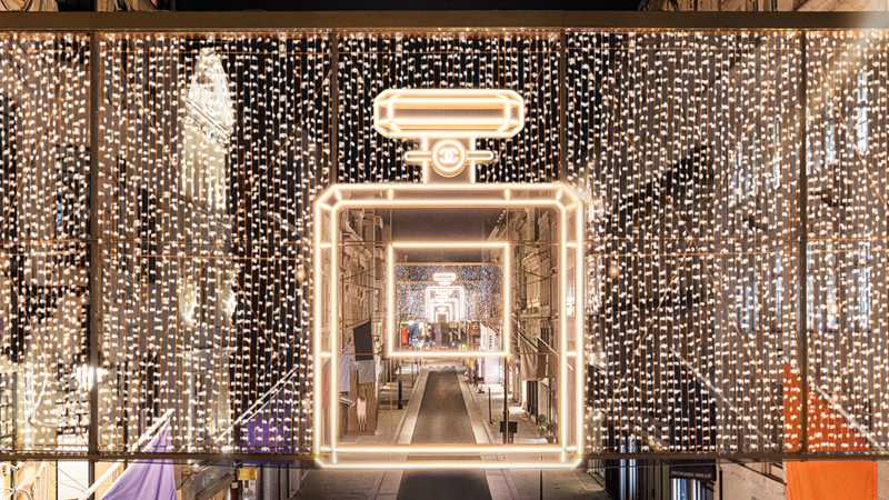 Admire this year's Bond Street Christmas lights in collaboration with Chanel, an ode to the fashion and beauty retailers that the area is known for. Credit: Bond Street. Image courtesy of Bond Street. Gold twinkling lights surround a giant Chanel perfume bottle made up of more gold lights on a banner above Bond Street at night