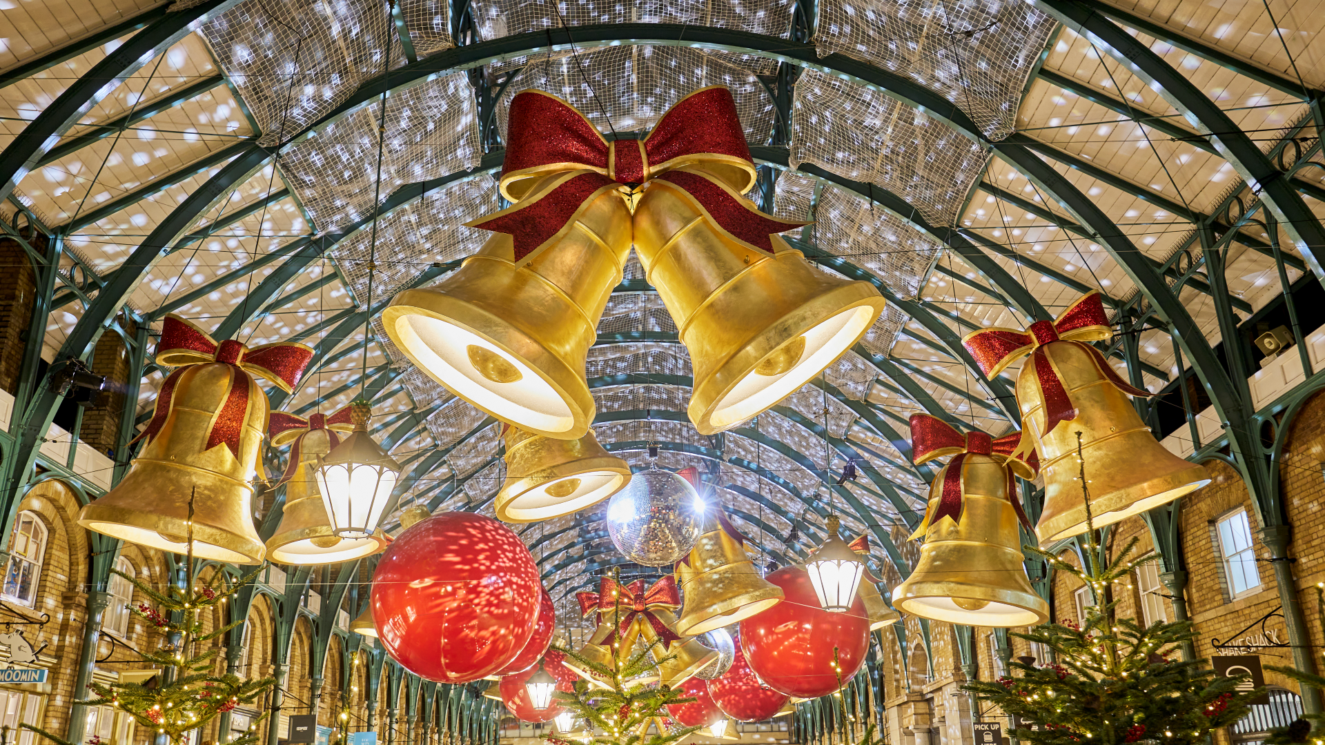 Get the perfect festive photo in front of Covent Garden's Christmas lights. Credit: Covent Garden. Image courtesy of Covent Garden. Giant gold bells with red bows and giant red baubles hang along the ceiling inside Covent Garden's covered market