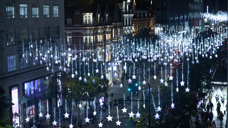 Head to Oxford Street where you'll find the famous starry light display, this year in collaboration with Great Ormond Street Hospital Charity. Credit: Doug Peters/PA Wire. Image courtesy of Four Agency. Hundreds of bright blue LED stars hang from garlands above Regent Street at night time with shops lining the street and people walking beneath