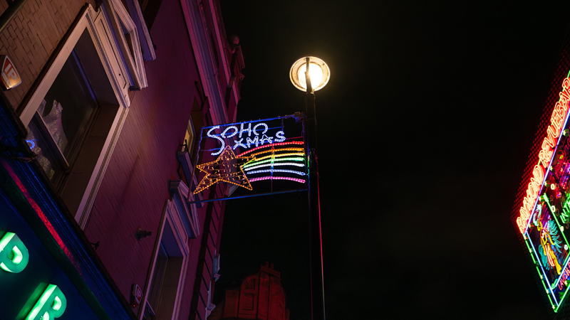 Don't miss the Soho Kids Xmas Lights that bring festive cheer to the district of Soho this Christmas. Credit: London Metropolitan University/Westminster Council. Image courtesy of Architecture for Kids. A rectangular panel of Christmas lights hang over Soho in the night sky with a shooting star in rainbow colours and the words "Soho Xmas" written above next to a round light pole with the top of Soho's illuminated shop fronts in the corners