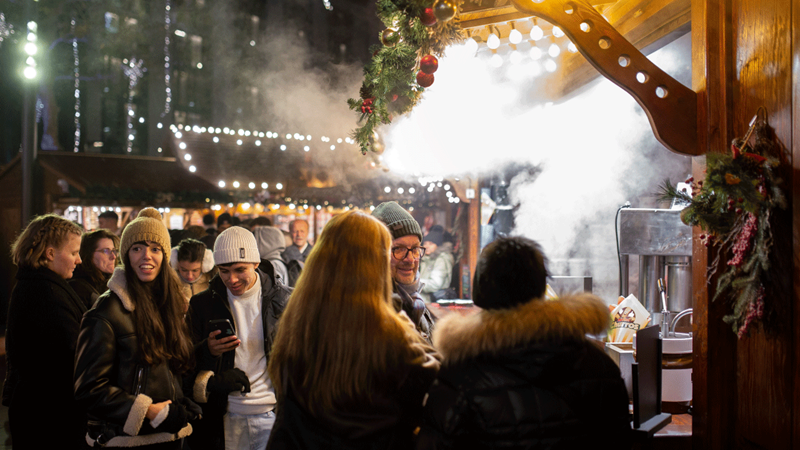 Warm up with a mulled wine and hot chocolate while you wander around one of London's top Christmas markets to suit any taste. Credit: Pasco Photography. Image courtesy of Underbelly. Crowds of people flock around a food vendor at Leicester Square Christmas market