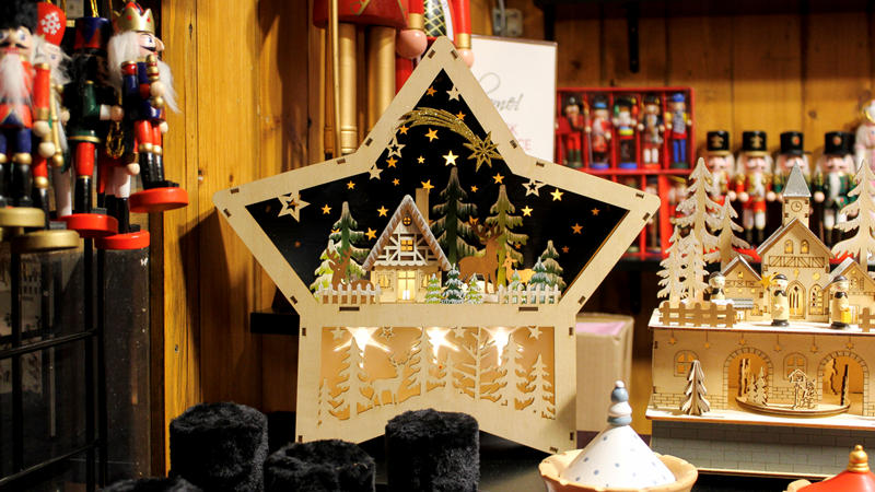 Find the perfect festive-themed gift for your loves ones at Kingston Christmas Market. Credit: Becky Greaves. Image courtesy of Kingston Christmas Market. A wooden star decoration with a snowy festive scene inside hanging inside one of the Christmas market stalls in Kingston surrounded by toy shoulders