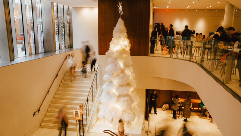 Visit the debut Christmas tree at the Royal Ballet and Opera, suitably dressed up in a tutu. Credit: 2024 Kirsty McLachlan. Andrej Uspenski, Artists of The Royal Ballet – Scarlett Harvey and Denilson Almeida. Image courtesy of The Royal Ballet and Opera. A tall white Christmas tree adorned with layers of fluffy decoration giving the impression of tutus with a large star on the top, surrounded by people in the theatre foyer