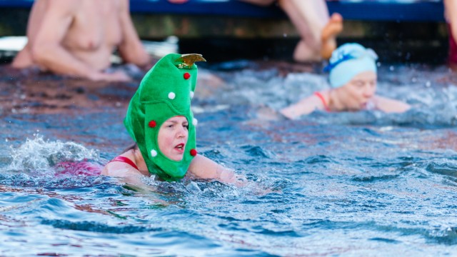 The Christmas Day Peter Pan Cup in Hyde Park. Credits: Serpentine Swimming Club. A woman wearing a green ornament on her head while swimming. Credits: Serpentine Swimming Club.