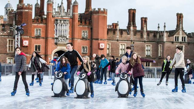 A photo of families skating at the Hampton Court Palace Ice Rink, with the palace in the background.